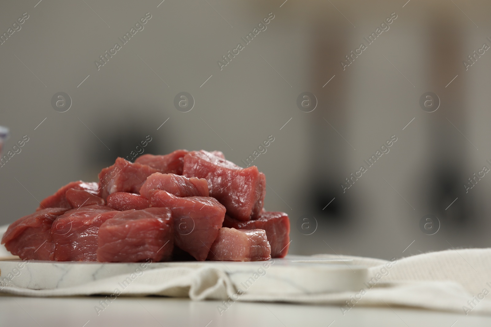 Photo of Pieces of raw beef on table against blurred background, closeup. Space for text