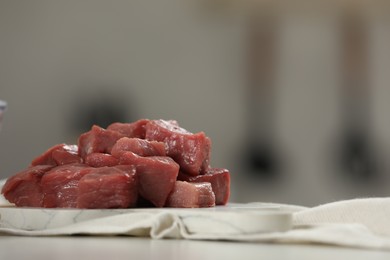 Pieces of raw beef on table against blurred background, closeup. Space for text