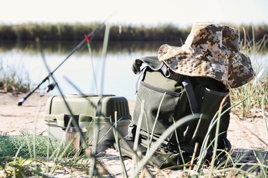 Photo of Bag with fishing essentials at riverside on sunny day