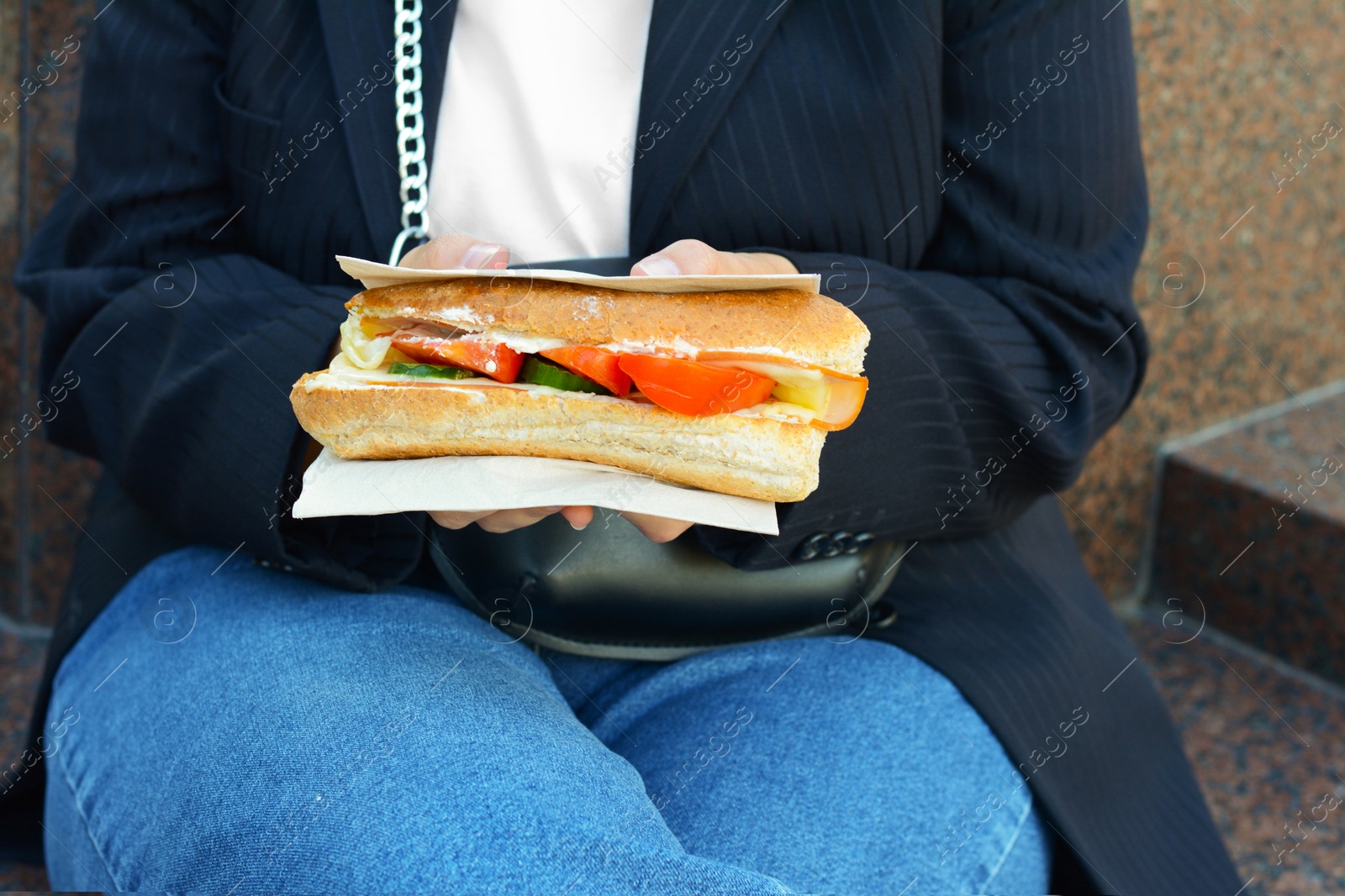 Photo of Woman holding tasty sandwich with vegetables outdoors, closeup. Street food