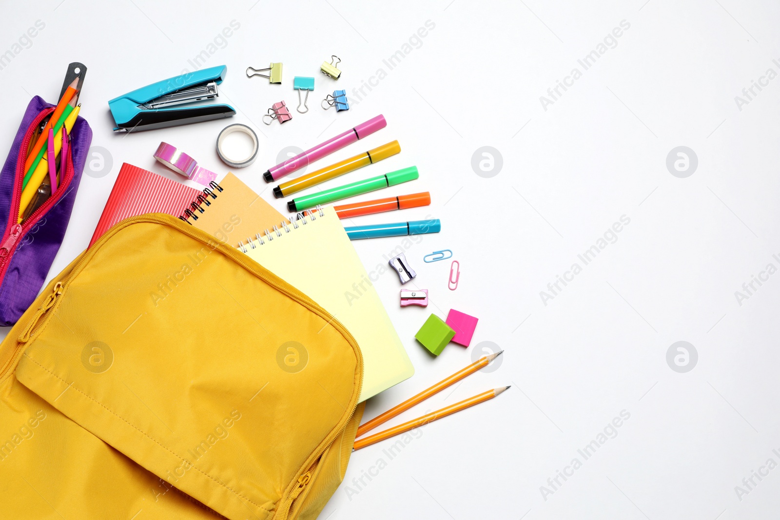 Photo of Backpack with different school stationery on white background, flat lay. Space for text