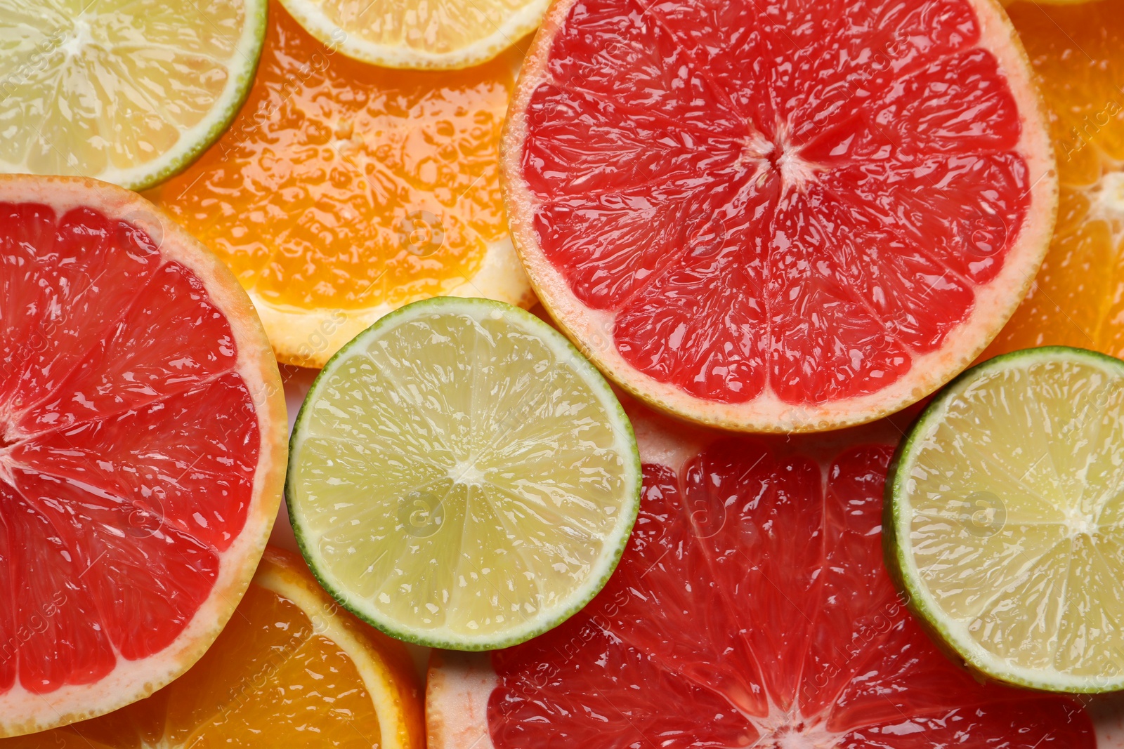 Photo of Slices of different citrus fruits as background, top view