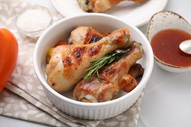 Photo of Marinade, roasted chicken drumsticks, rosemary and tomatoes on white table