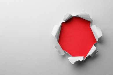 Hole in white paper on red background, space for text