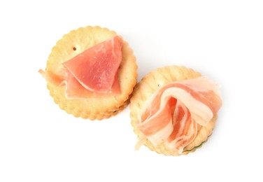 Delicious crackers with prosciutto on white background, top view