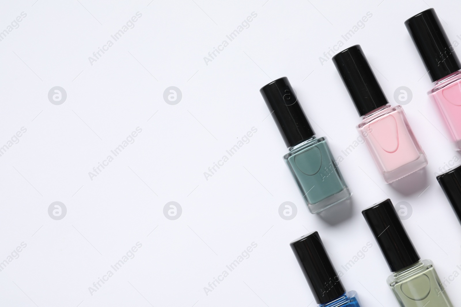 Photo of Nail polishes on white background, flat lay. Space for text