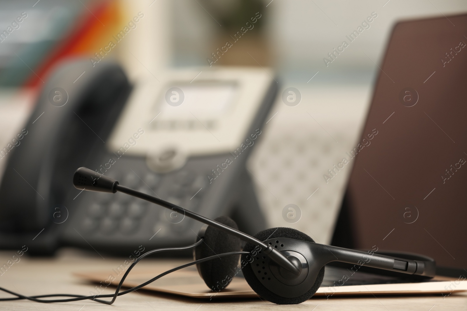 Photo of Headset and laptop on table indoors, closeup. Hotline concept