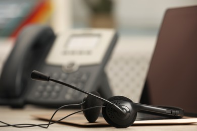 Headset and laptop on table indoors, closeup. Hotline concept