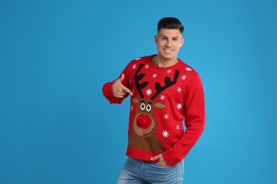 Photo of Happy man pointing on his Christmas sweater against blue background