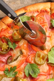 Cutting delicious pizza Diablo at table, closeup