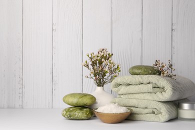 Photo of Composition with different spa products and flowers on white table against wooden background. Space for text