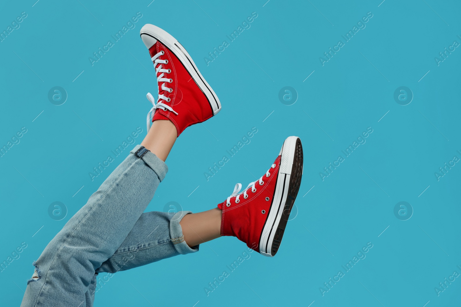 Photo of Woman in stylish gumshoes on light blue background, closeup. Space for text