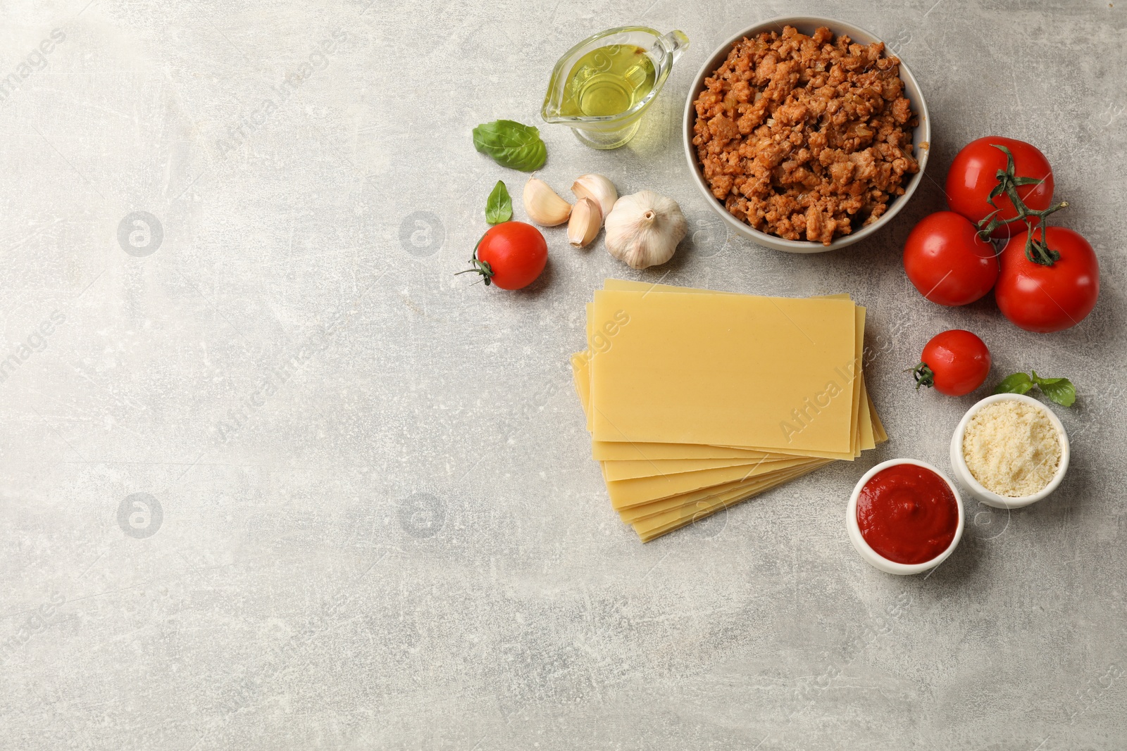 Photo of Flat lay composition with products for cooking lasagna on grey textured table. Space for text