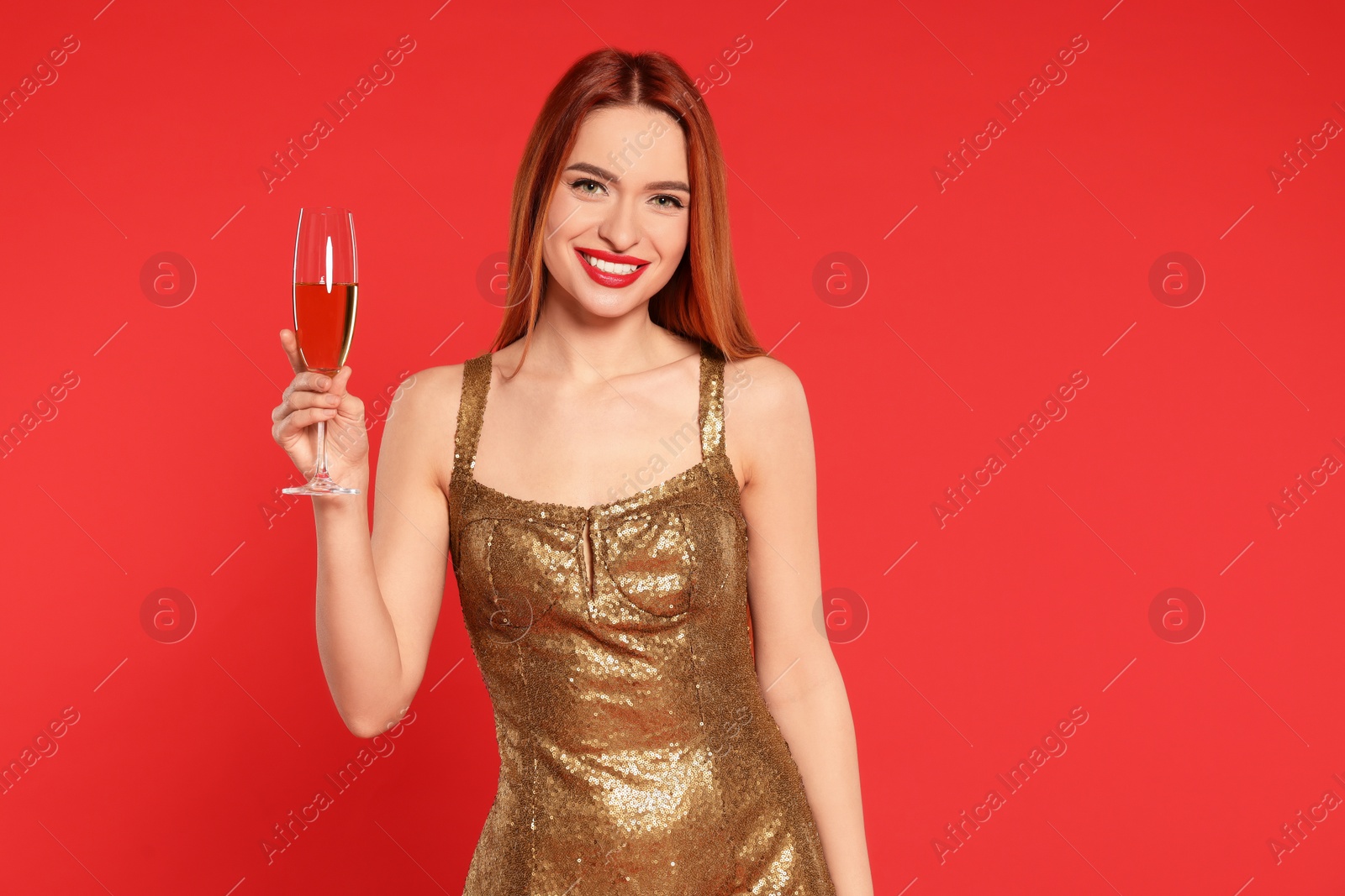 Photo of Young woman in dress with glass of wine on red background