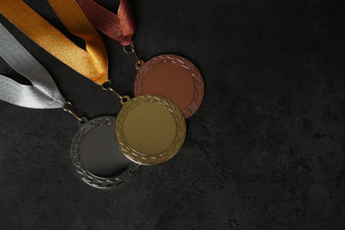 Gold, silver and bronze medals on grey stone background, flat lay. Space for design