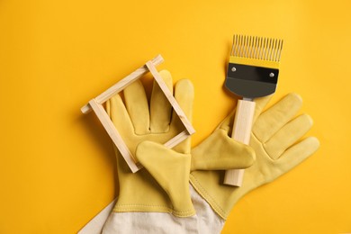 Photo of Beekeeping tools on yellow background, flat lay