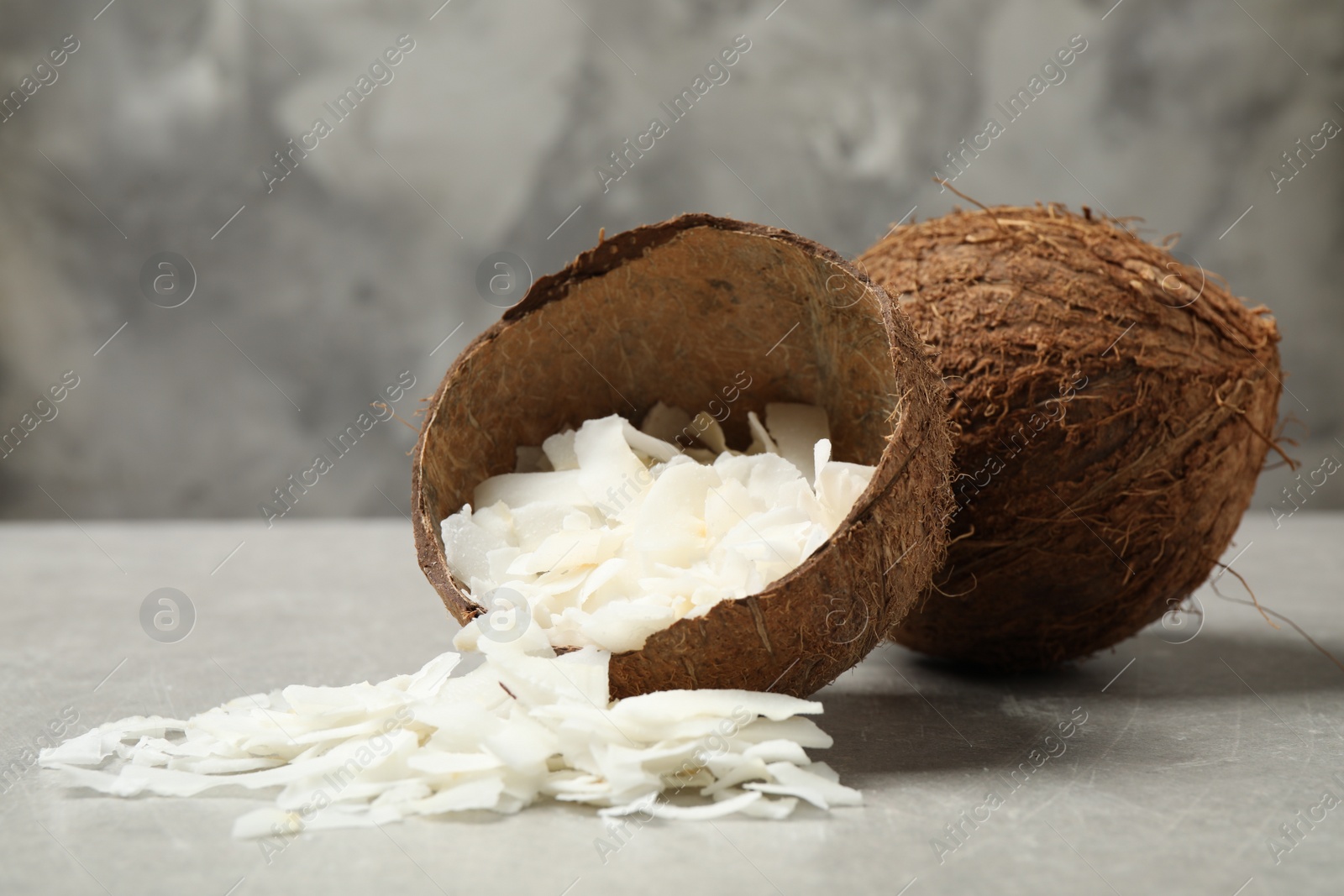 Photo of Tasty coconut chips and shell on grey table