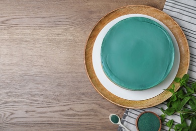 Photo of Delicious homemade spirulina cheesecake served on wooden background, top view. Space for text