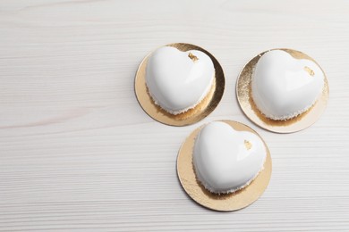 St. Valentine's Day. Delicious heart shaped cakes on white wooden table, flat lay. Space for text