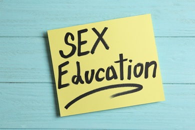Photo of Note with phrase "SEX EDUCATION" on light blue wooden background, top view
