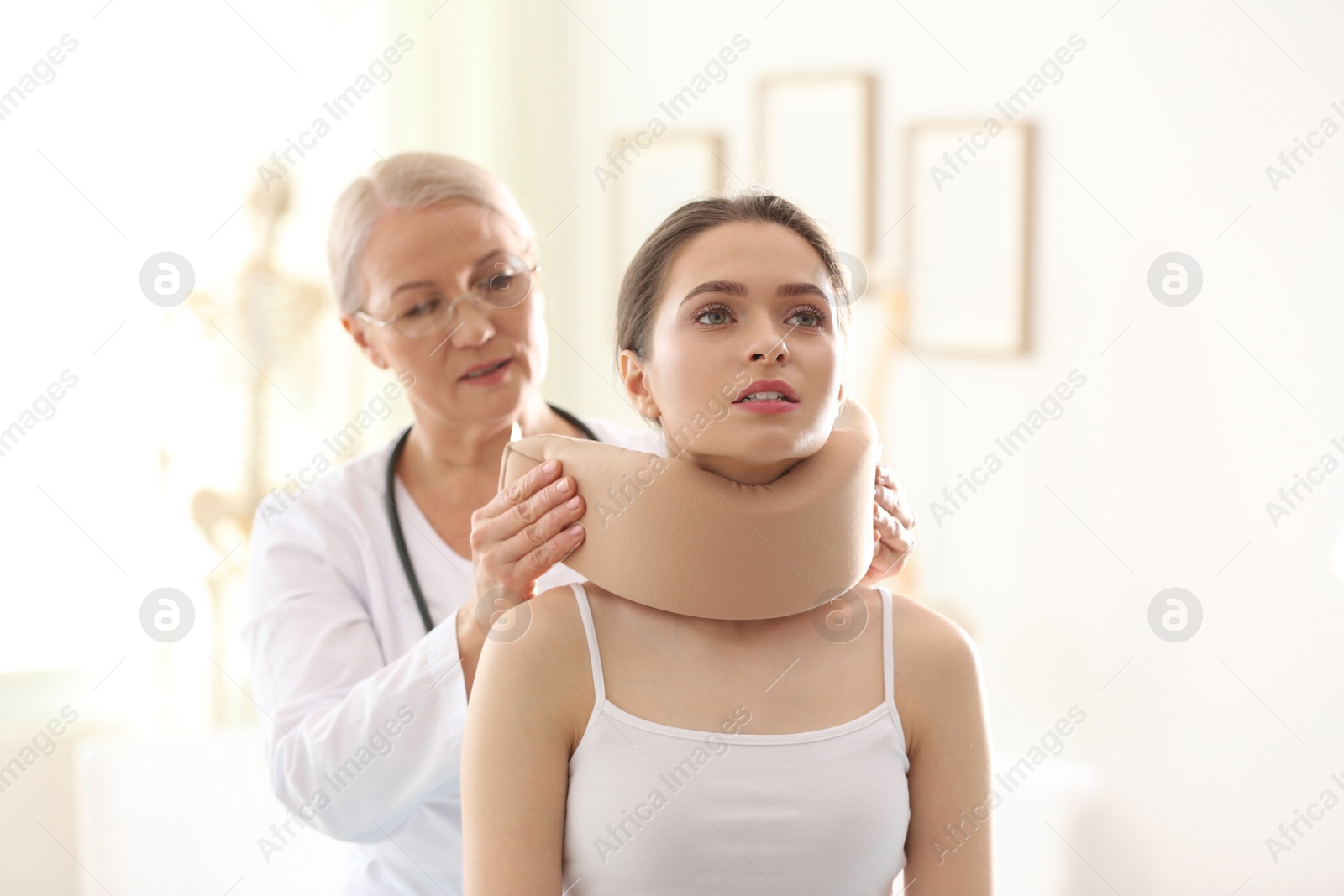 Photo of Female orthopedist applying cervical collar onto patient's neck in clinic