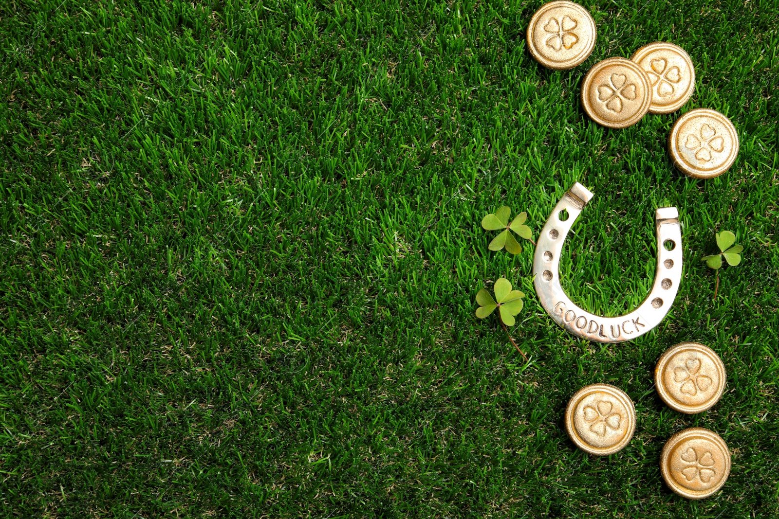 Photo of Flat lay composition with horseshoe on grass, space for text. St. Patrick's Day celebration