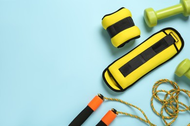 Yellow weighting agents and sport equipment on light blue background, flat lay. Space for text