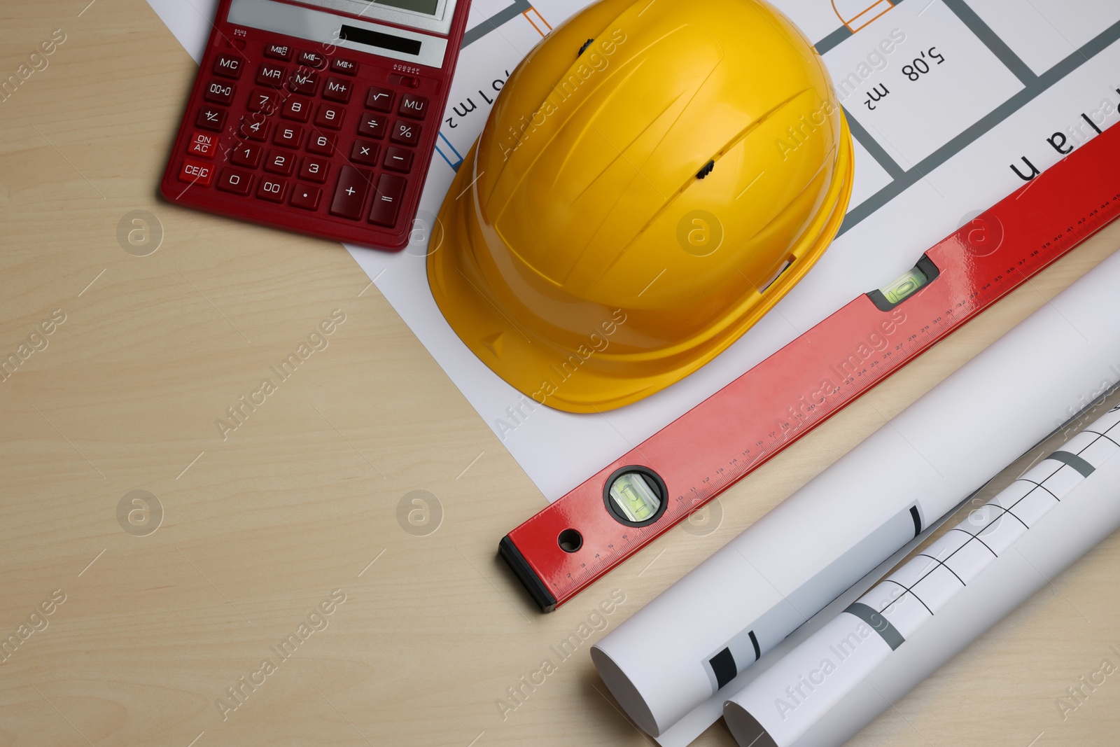 Photo of Construction drawings, safety hat, calculator and bubble level on wooden table, flat lay. Space for text