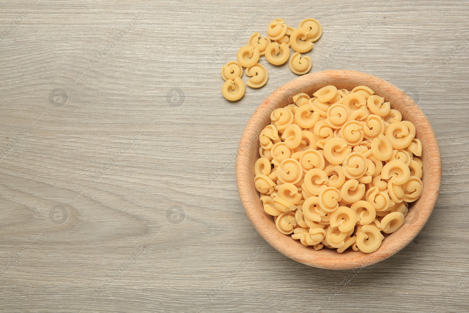 Photo of Raw dischi volanti pasta in bowl on light grey wooden table, top view. Space for text