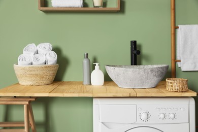 Photo of Wooden countertop on washing machine in laundry. Interior design