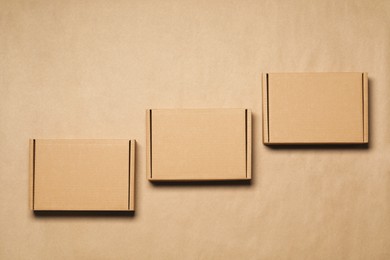 Photo of Closed cardboard boxes on light brown background, flat lay