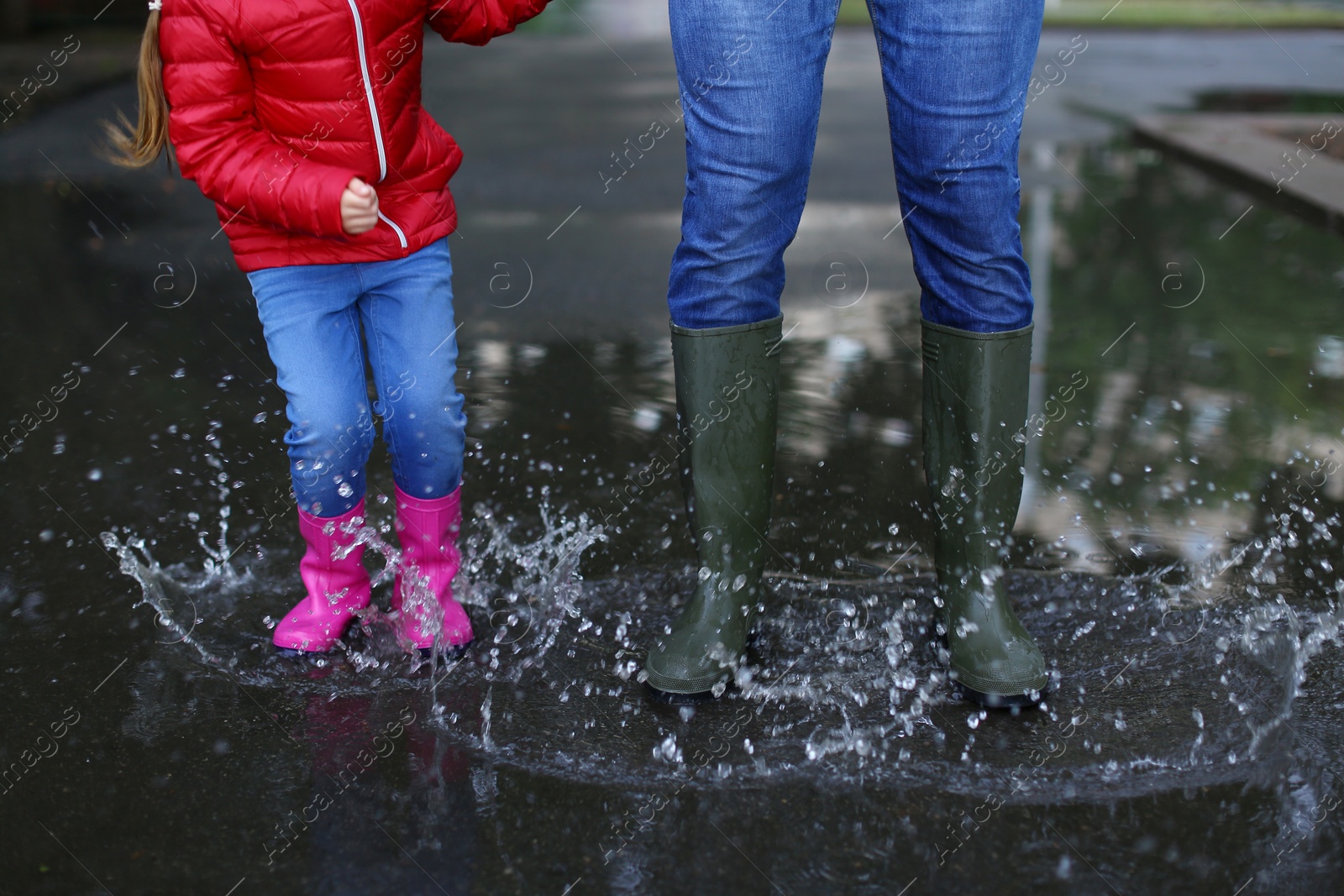 Image of Father and daughter in rubber boots outdoors after rain, closeup