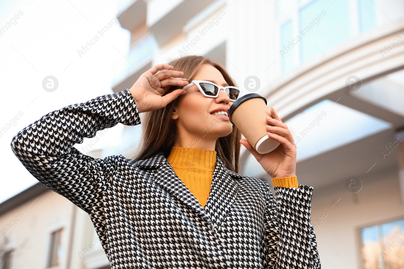 Photo of Young woman with cup of coffee on city street in morning