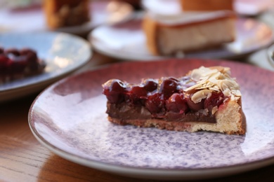 Photo of Plate with slice of cherry cake on wooden table