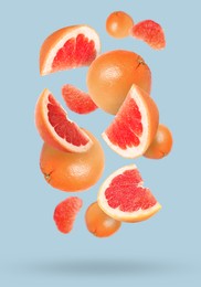 Image of Tasty ripe grapefruits falling on light background