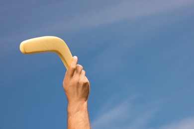 Photo of Man throwing boomerang against blue sky, closeup. Space for text