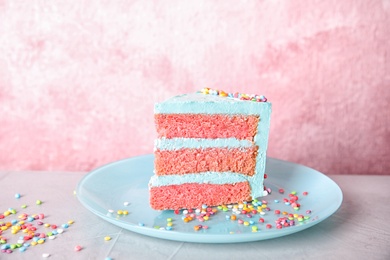 Slice of fresh delicious birthday cake on table against color background