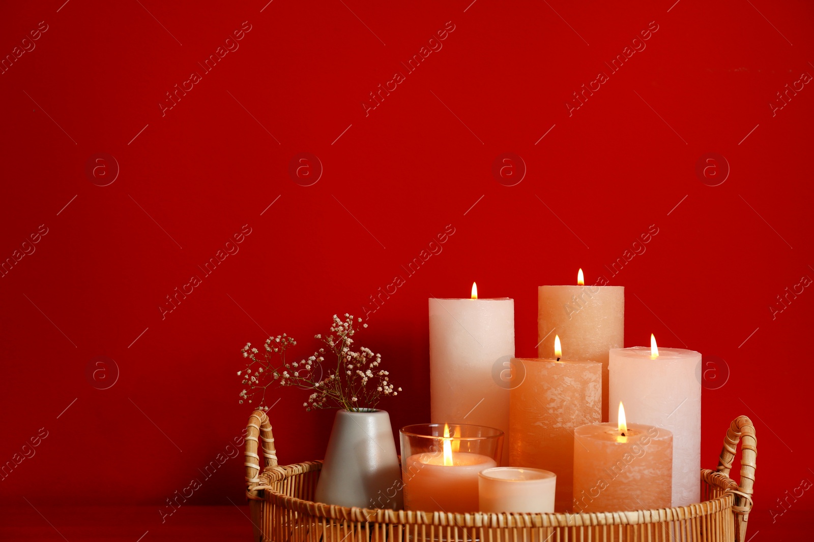 Photo of Tray with burning candles on red background. Space for text