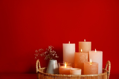 Tray with burning candles on red background. Space for text