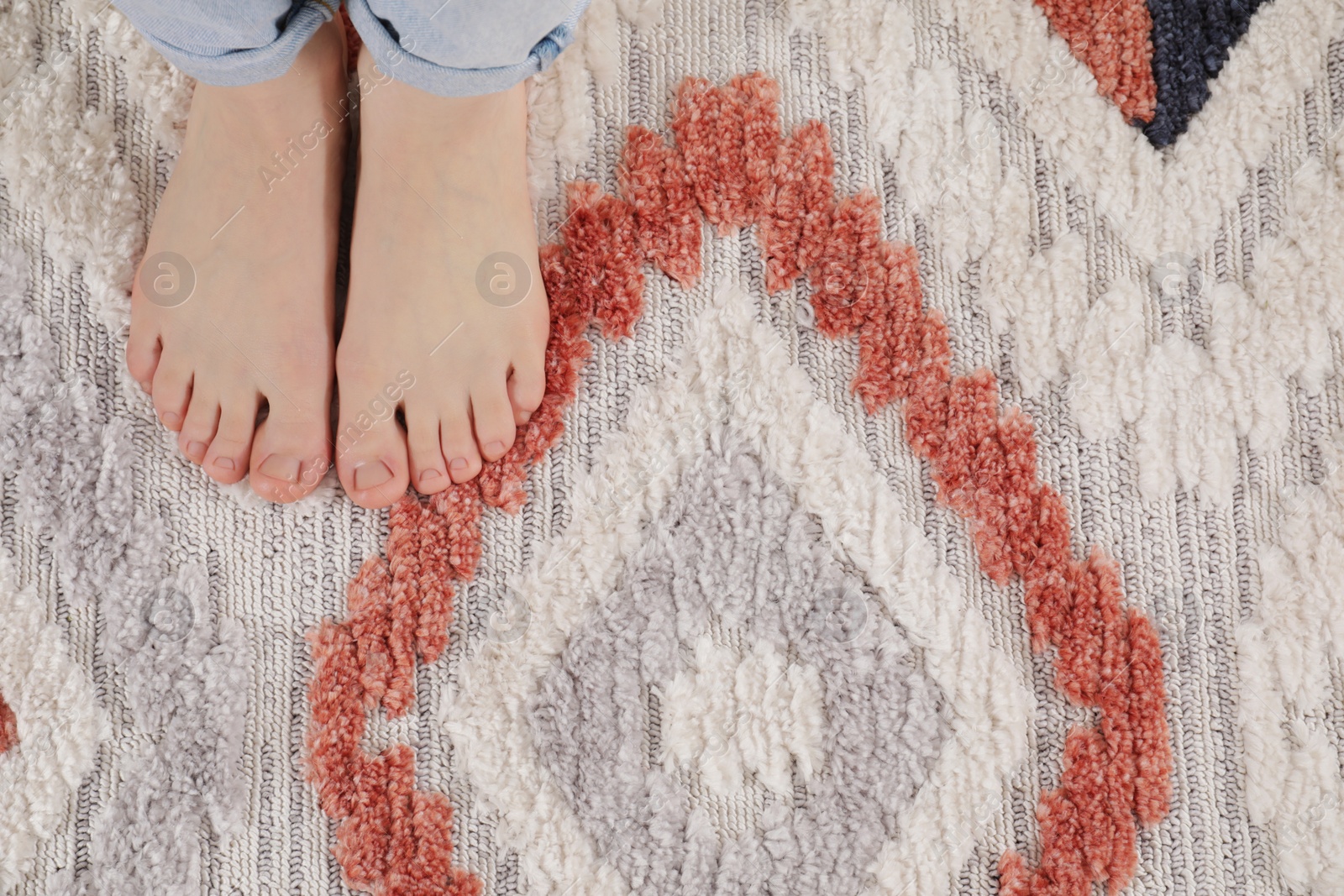 Photo of Woman standing on carpet with pattern at home, top view