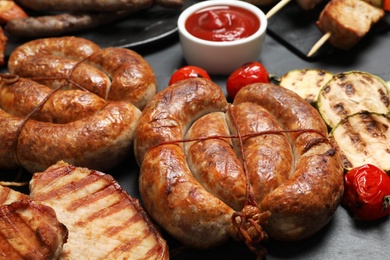 Barbecued meat and vegetables on grey table, closeup