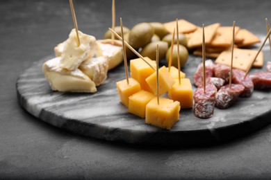 Photo of Toothpick appetizers. Pieces of cheese and sausage on black table, space for text