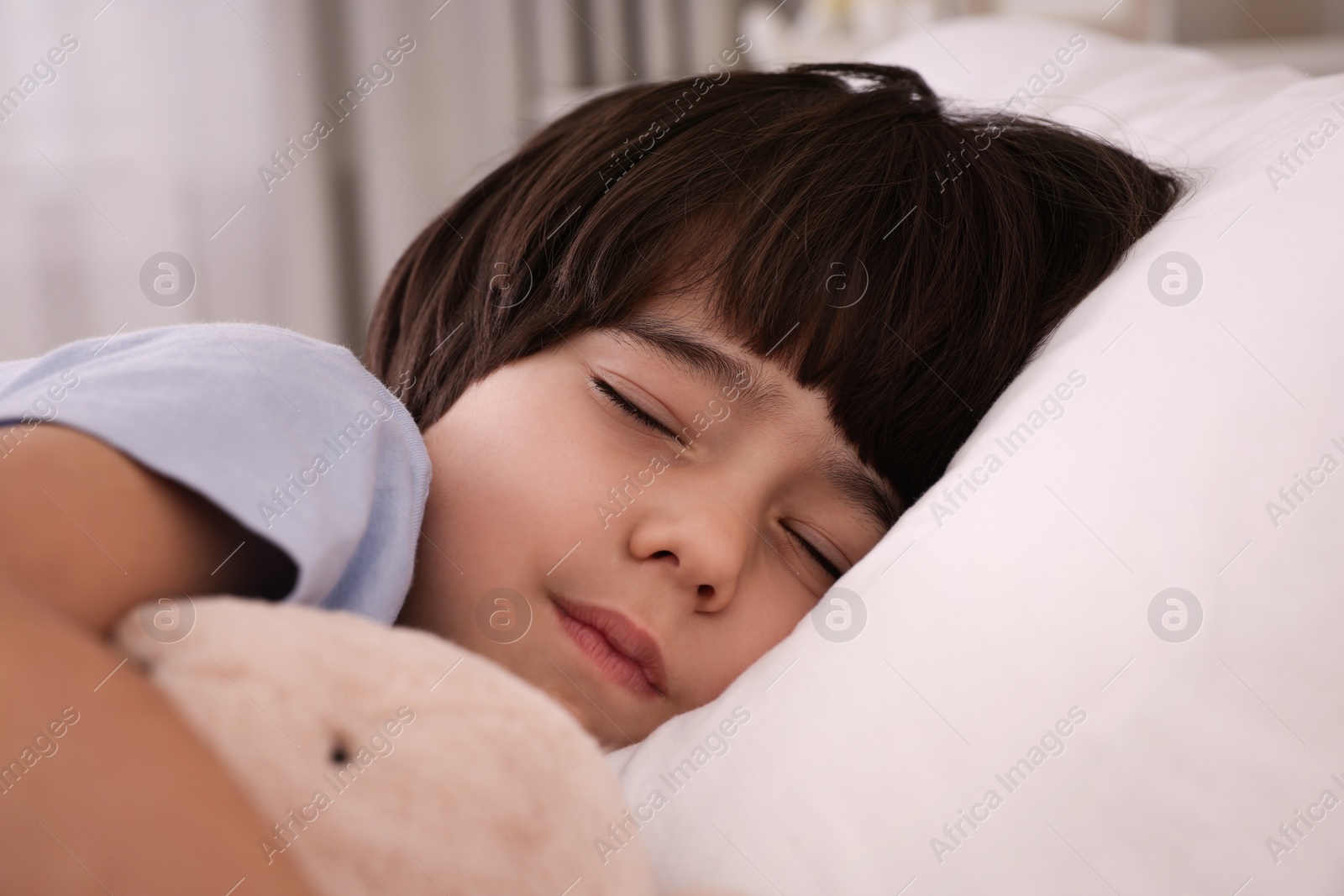 Photo of Cute little boy with toy sleeping in bed at home, closeup
