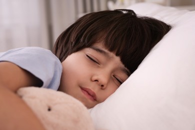 Photo of Cute little boy with toy sleeping in bed at home, closeup