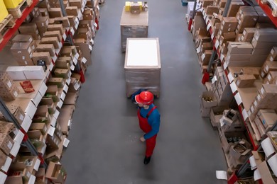 Image of Man in hardhat working with pallet truck at warehouse, above view. Logistics center