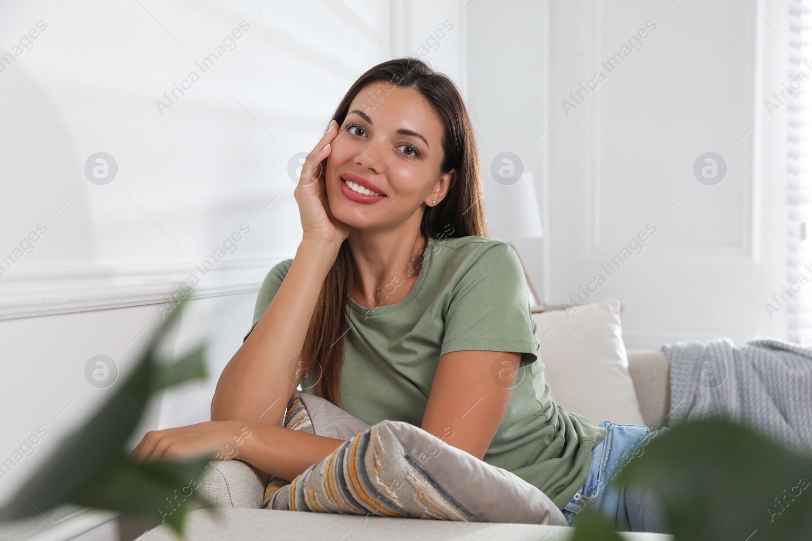 Photo of Beautiful woman sitting on sofa at home