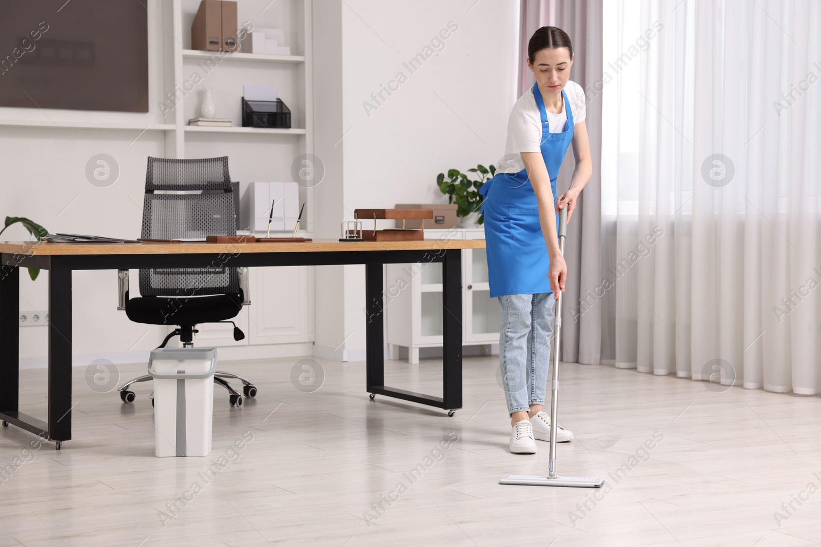 Photo of Cleaning service. Woman washing floor with mop in office