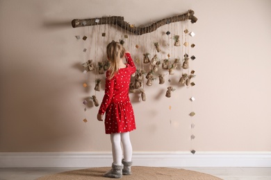 Little girl taking gift from New Year advent calendar indoors