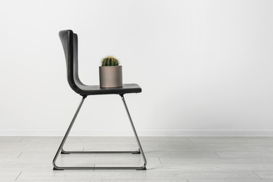 Chair with cactus near white wall, space for text. Hemorrhoids concept