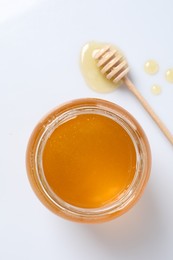 Photo of Tasty honey in glass jar and dipper isolated on white, top view